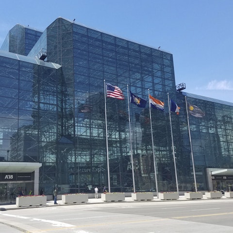 U.S. flag and others flying in front of a glass building