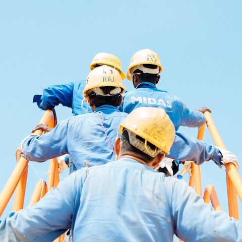 workers wearing hard hats climbing a staircase into the sky