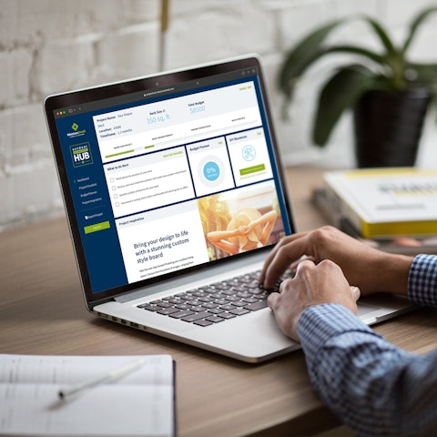 man sitting at a desk working on a laptop with the MoistureShield Project Hub displayed