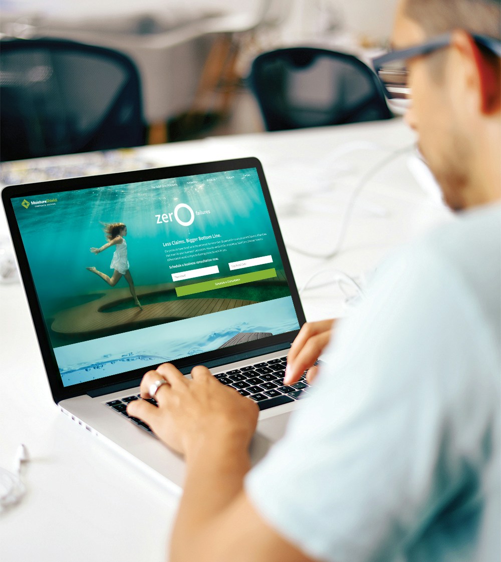 man working on laptop with moistureshield ad displayed