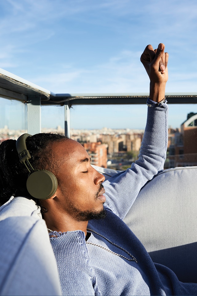 man on rooftop relaxing and listening to music