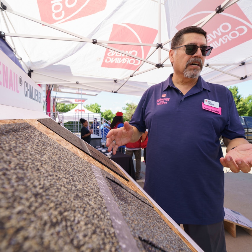 Owens Corning shingle board with man standing next to it talking