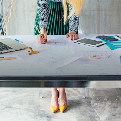 women at desk studying floor plan