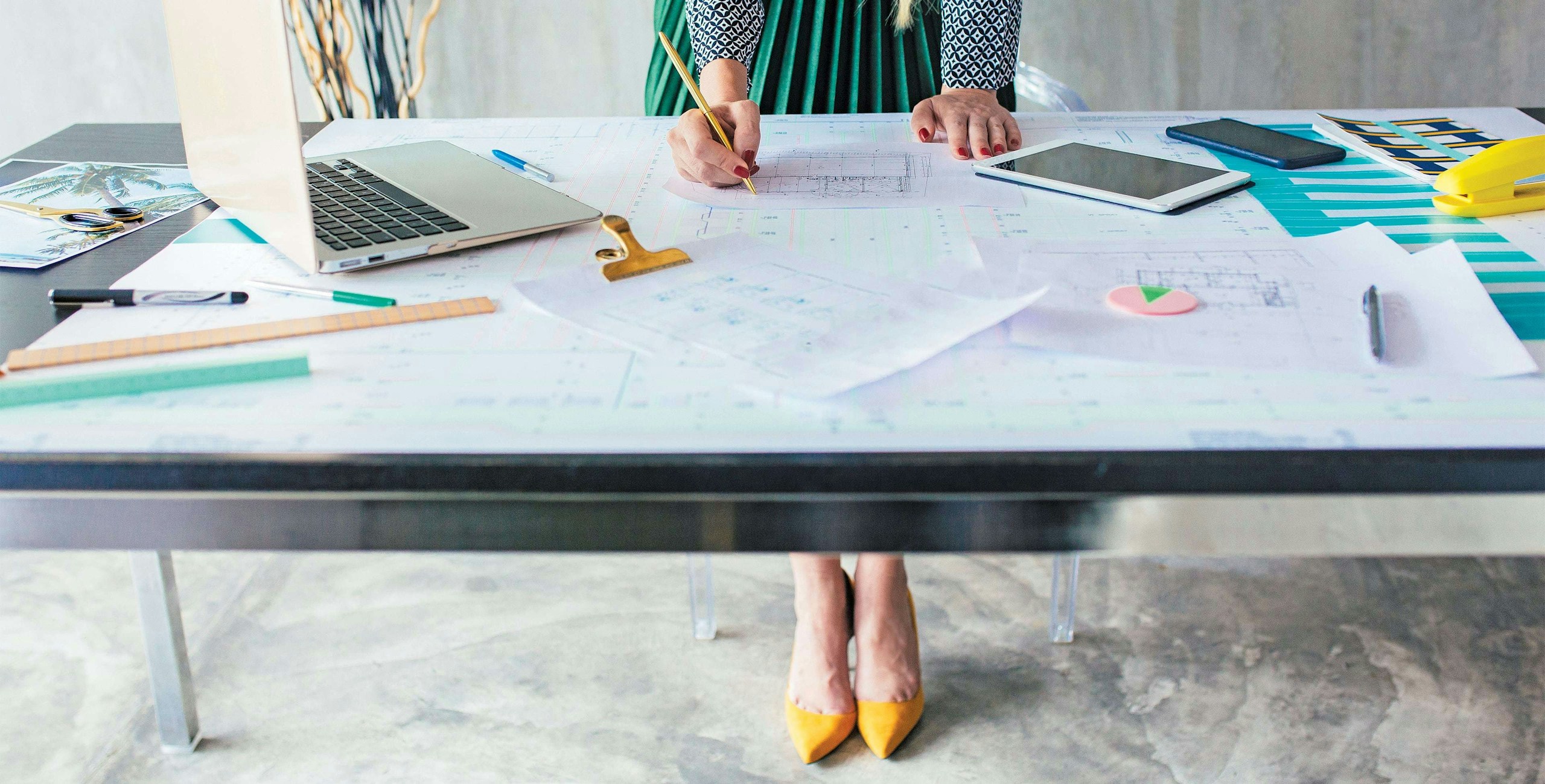 women leaning over desk studying blue prints