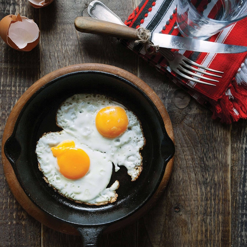 cooked eggs in a skillet on a wood cooling plate