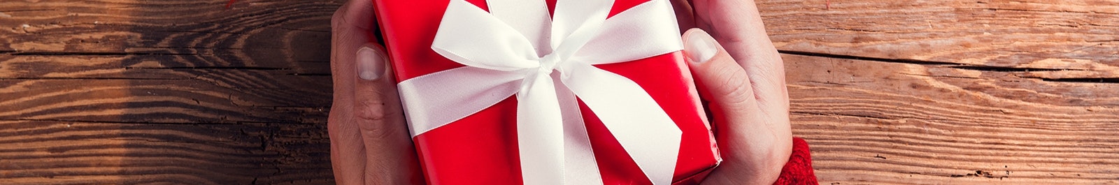 two hands hold a red box with a white bow