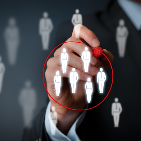person drawing a red circle around a group of human figures on a clear horizontal board