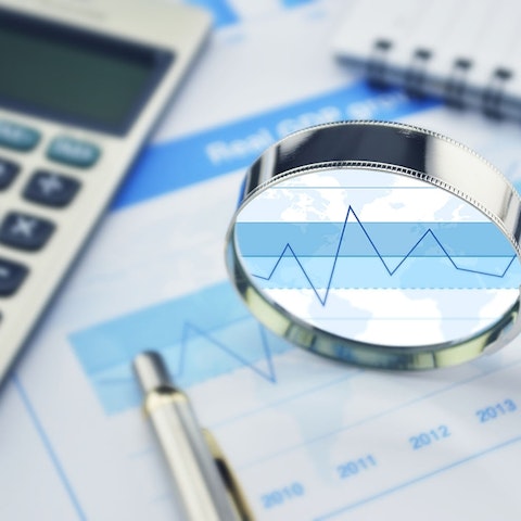 financial report with a calculator, pen and magnifying glass laying on top of it