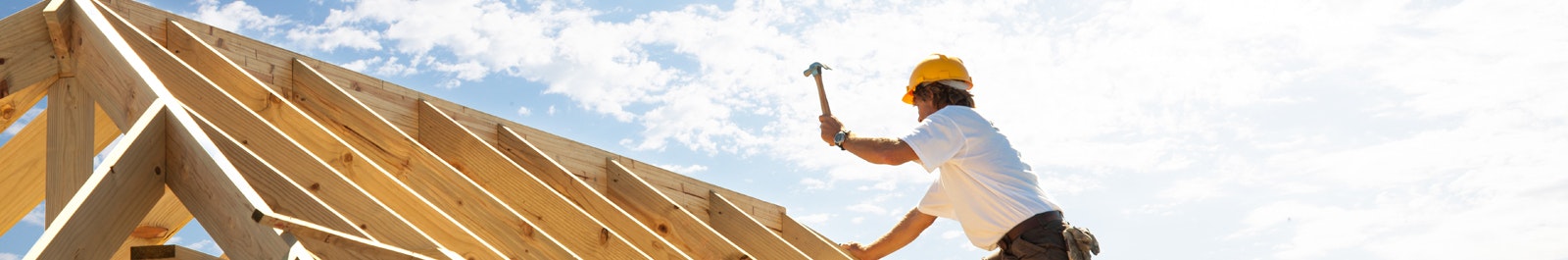 framing contractor working on a roof against a blue sky