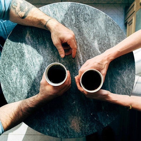 overhead view of two people at a table with coffee cups