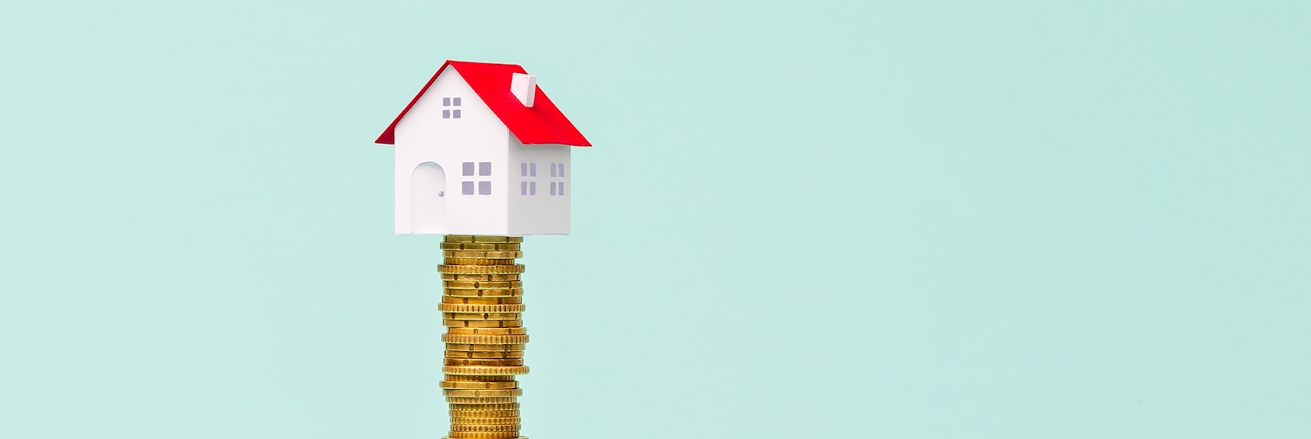 Home sitting on top of a stack of gold coins