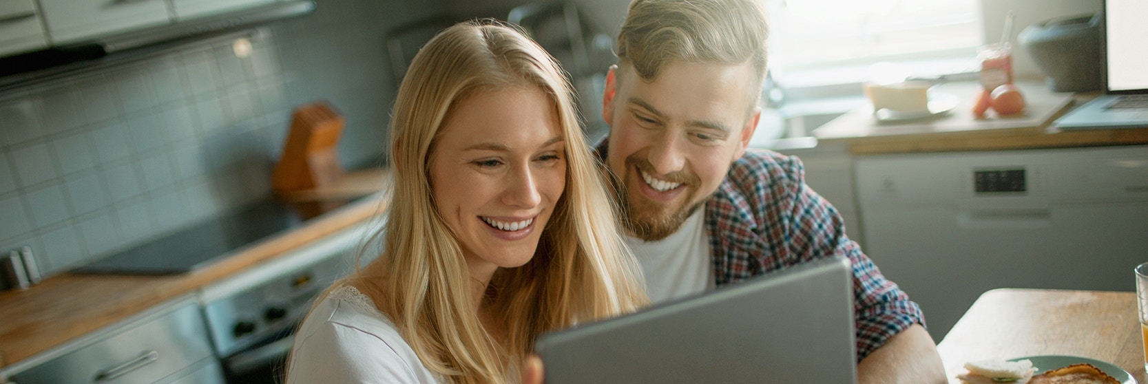 couple sitting at a kitchen table working on a laptop